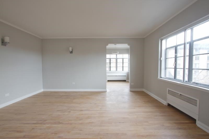 an empty living room with wood floors and large windows