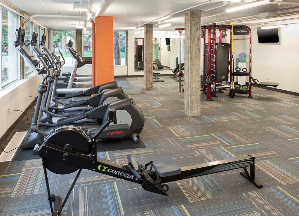 a gym with cardio equipment and weights on the floor