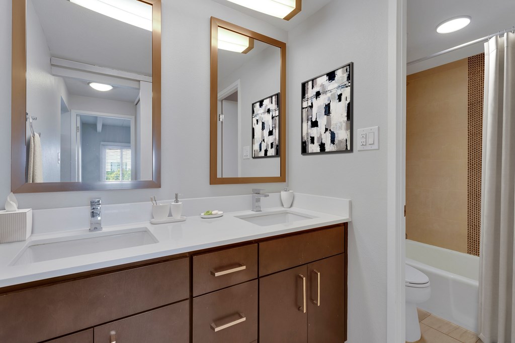 A bathroom with a white counter top and brown drawers.