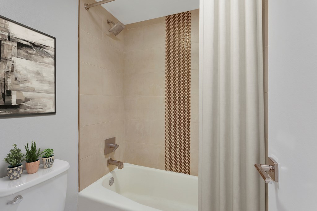 A bathroom with a white tub and a shower with a gold screen.