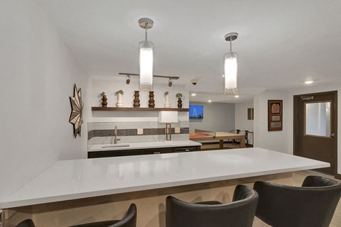 a kitchen with a white counter top and chairs