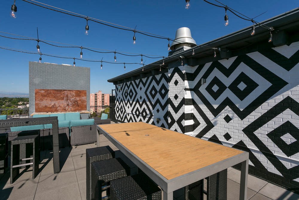 a rooftop patio with tables and chairs and a geometric wall