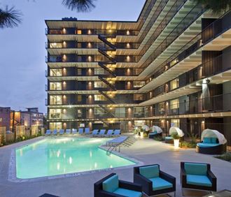 a swimming pool in front of a tall building at night