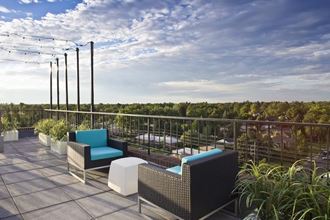 a balcony with chairs and plants and a view of the sky