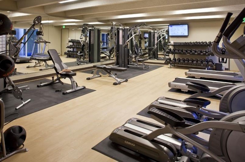 a gym with cardio equipment and weights on a wooden floor