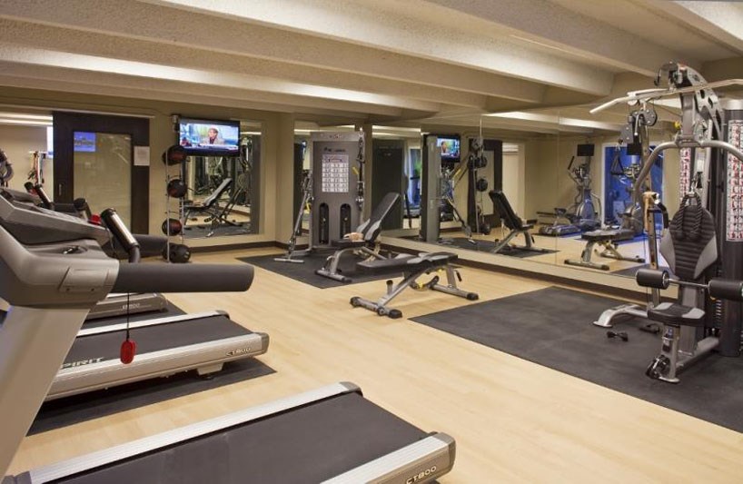 a gym with cardio machines and weights on a wooden floor