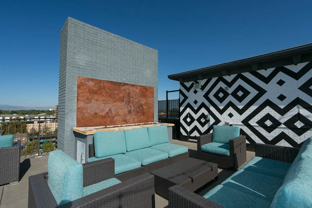 a rooftop patio with couches and chairs and a fireplace