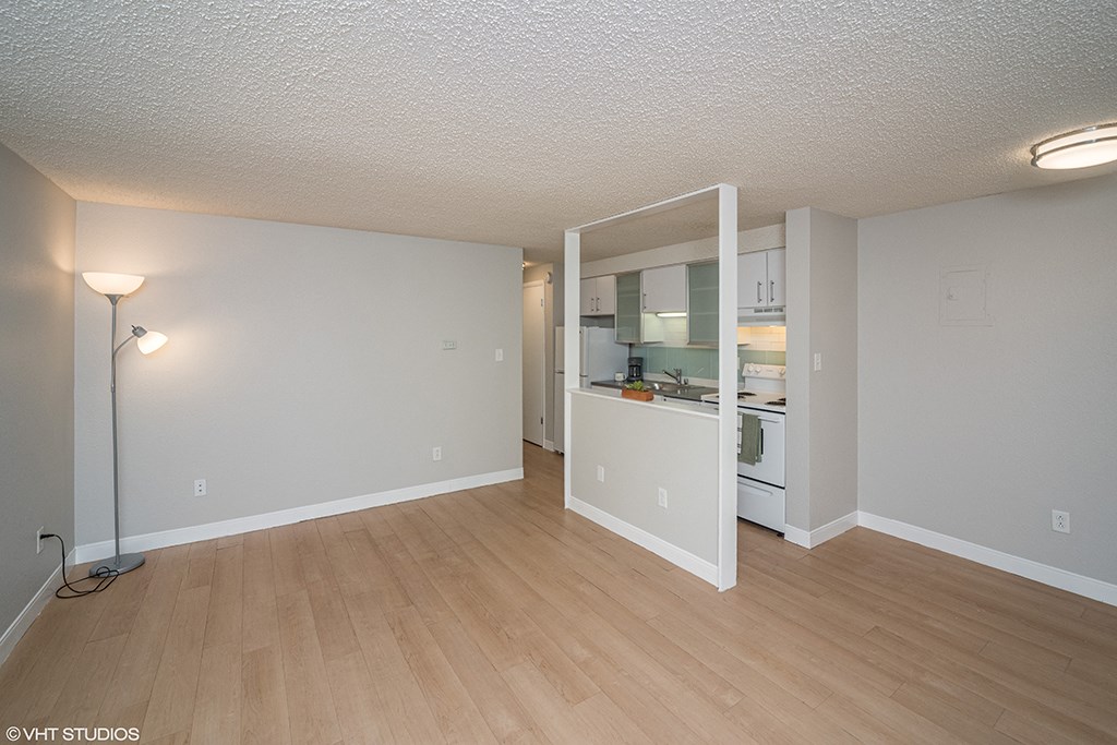 the living room and kitchen of an apartment with wood flooring