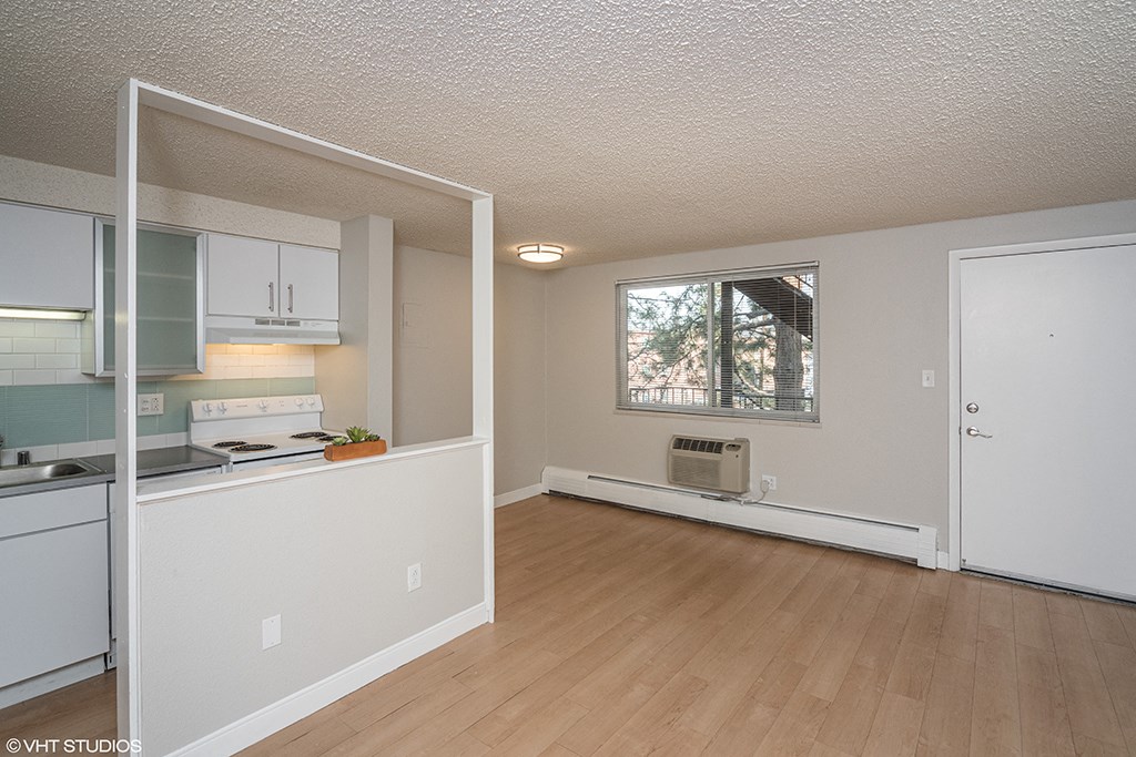 an empty living room and kitchen with wood flooring and a window