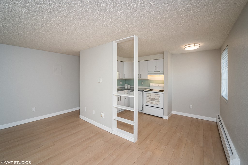 an empty living room and kitchen with a wood floor