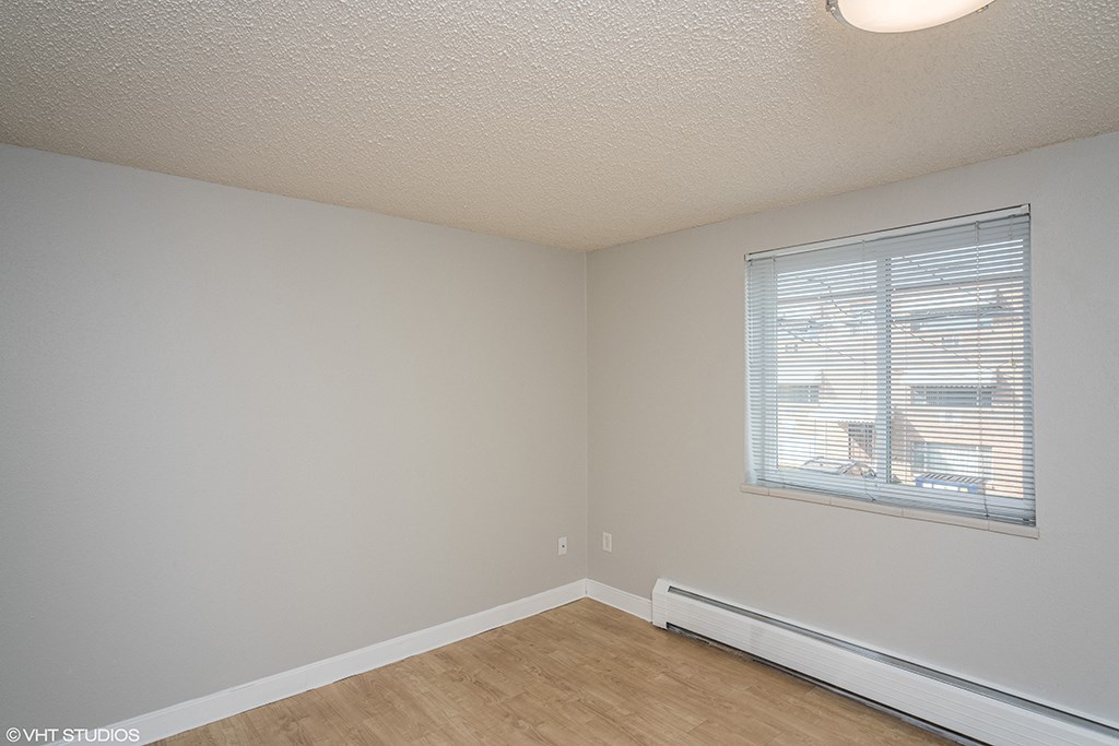 an empty room with a window and a wooden floor