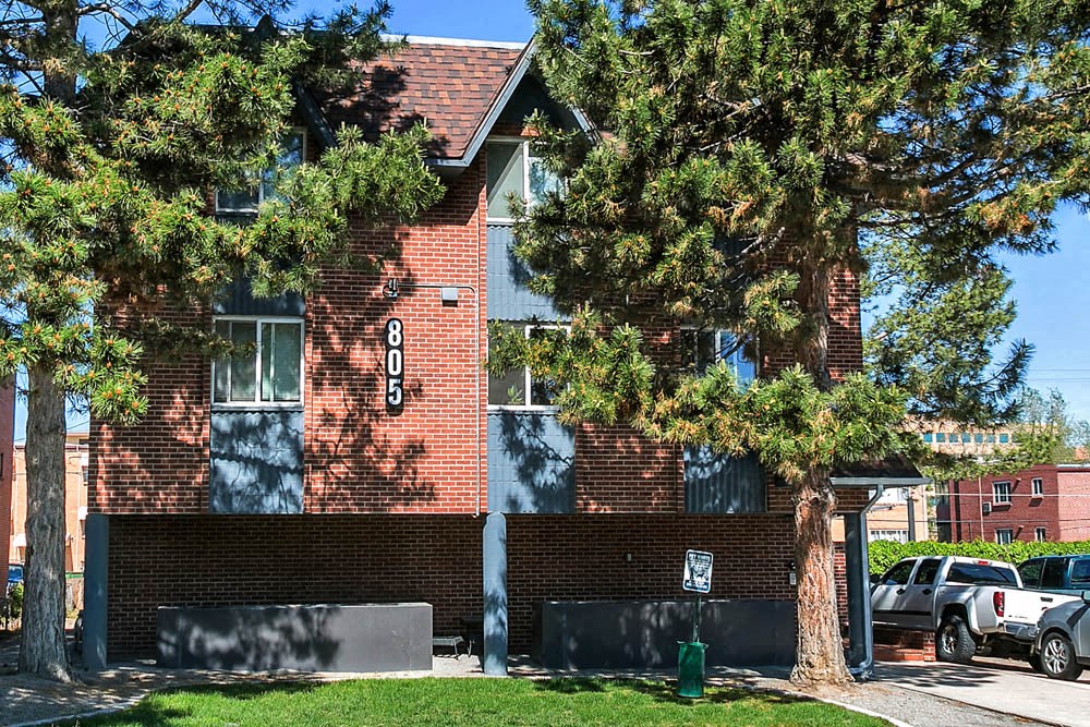 a red brick house with a tree in front of it