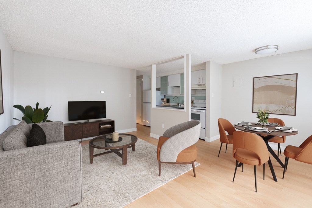 A living room with a grey couch, a brown chair, a brown table and a television.