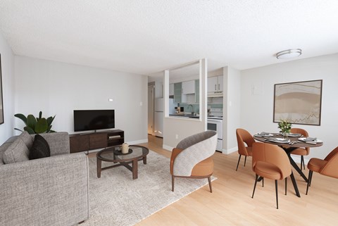A living room with a grey couch, a brown chair, a brown table and a television.