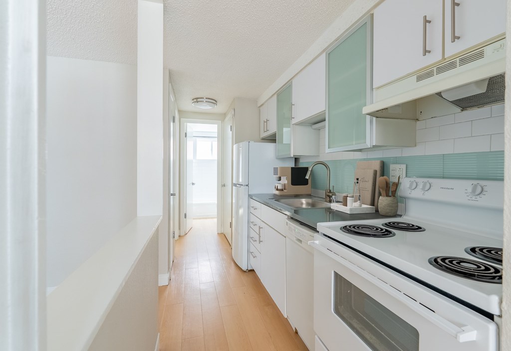 A kitchen with white appliances and wooden floors.
