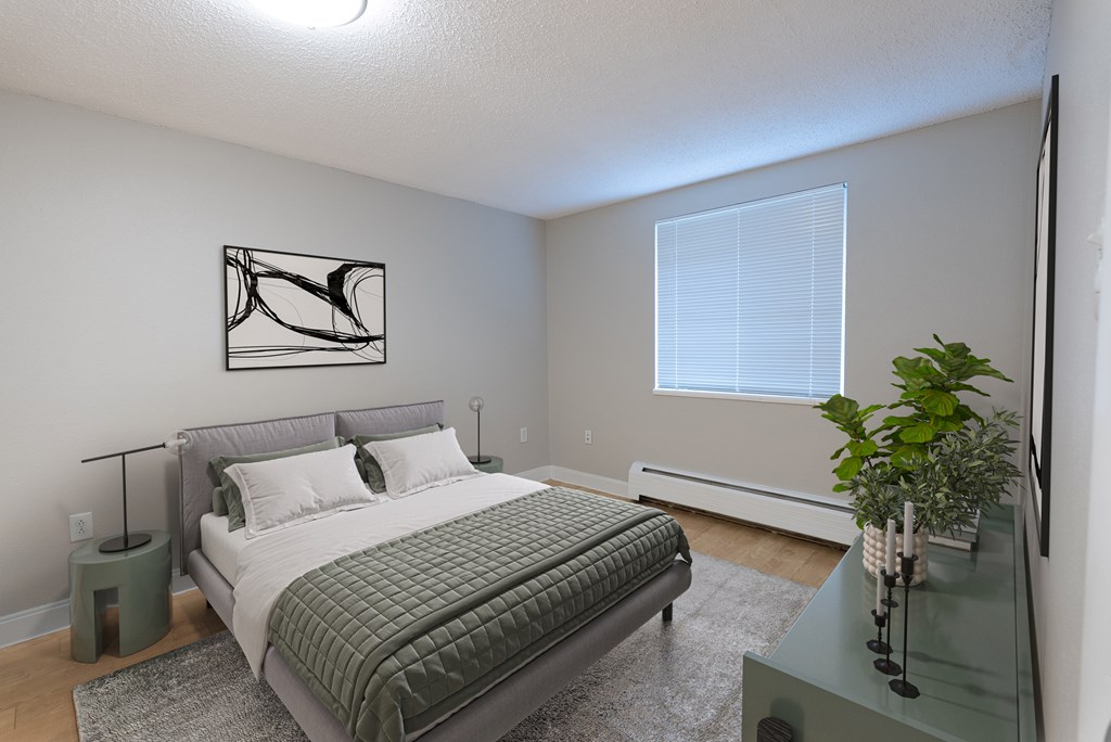 A bedroom with a bed, nightstand, and a plant.