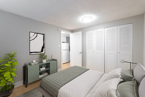 A bedroom with a bed, nightstand, and a plant.
