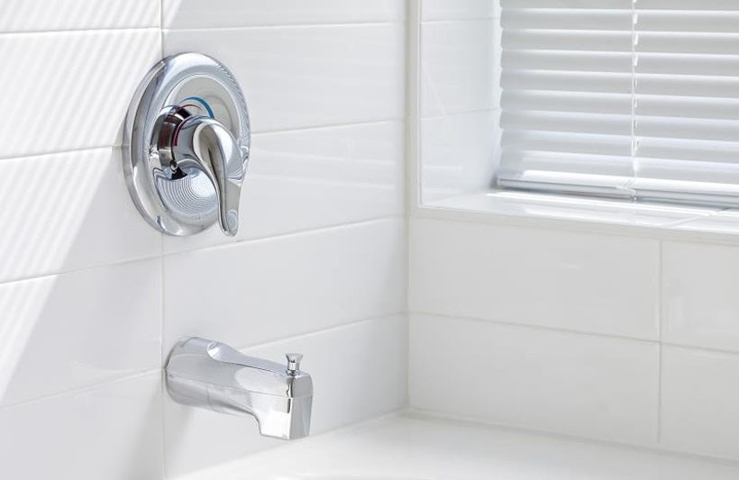 a white tiled bathroom with a silver faucet and a window