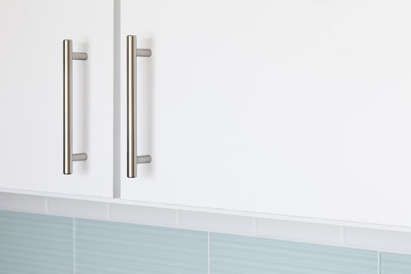 three silver handles on a white bathroom cabinet