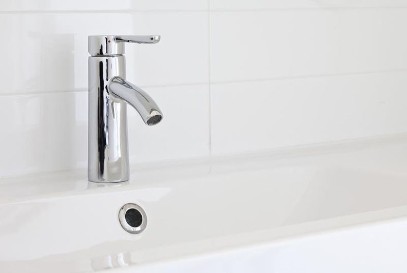 a white bathroom with a sink and a faucet