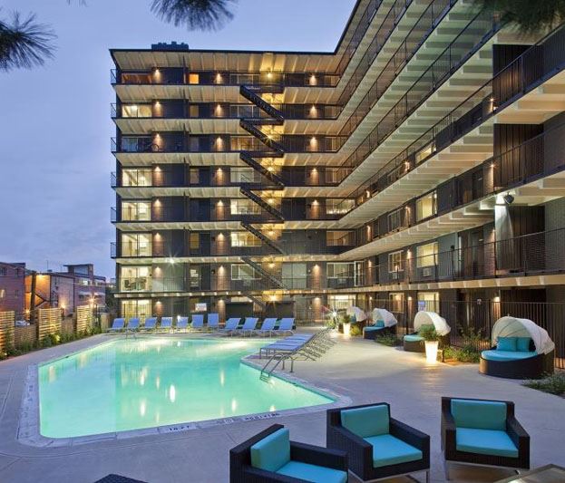 a swimming pool in front of a tall building at night