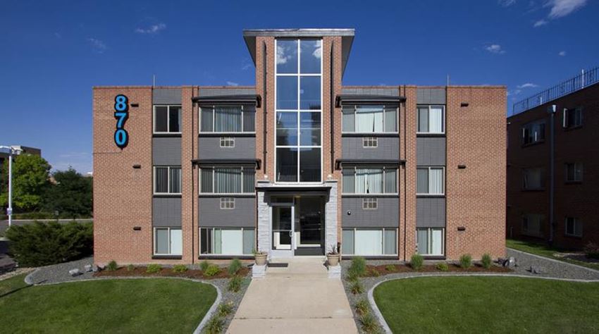 a brick apartment building with a sidewalk in front of it