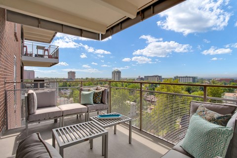 A balcony with a table and chairs overlooking a cityscape.