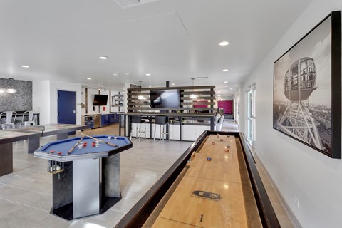 A pool table is in the middle of a room with a television and a picture on the wall.