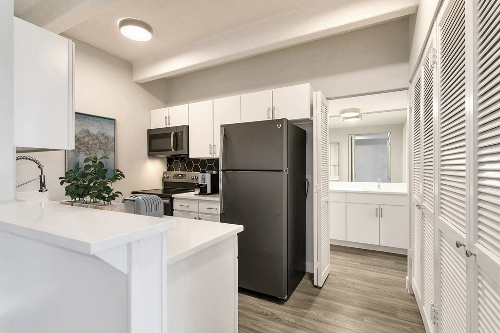 a white kitchen with a black refrigerator and a sink