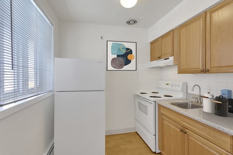 a kitchen with white appliances and wooden cabinets and a window