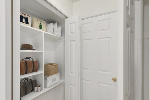 a closet with white doors and shelves with bags and purses