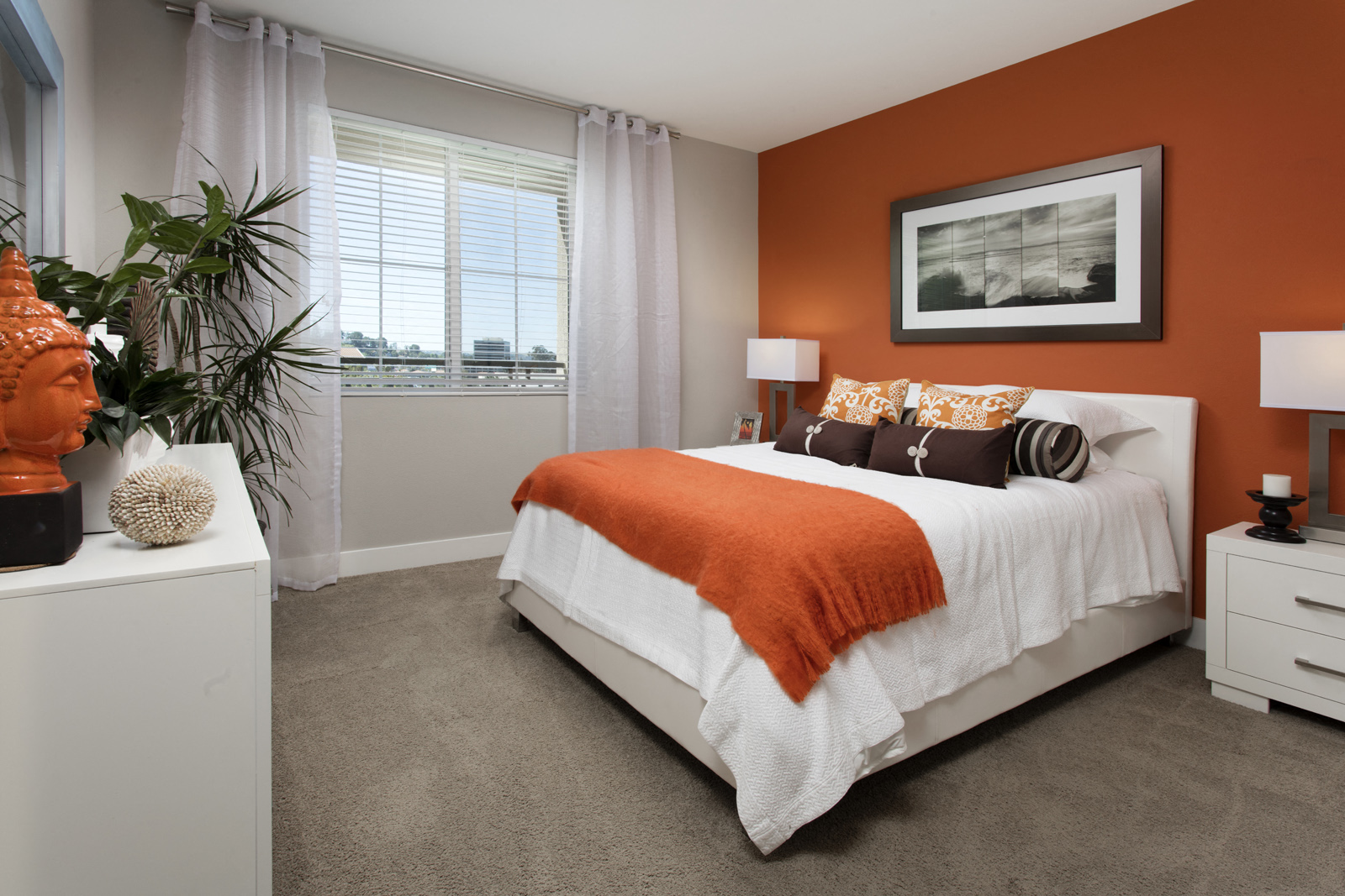 bedroom with white bed and orange accent wall and carpeted flooring
