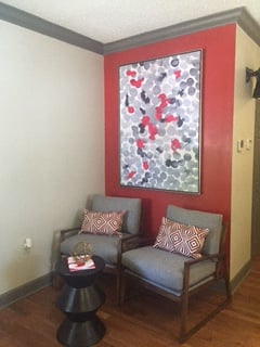 a living room with two chairs and a painting on the wall