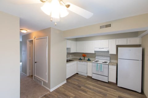 a kitchen with white appliances and white cabinets and a white ceiling fan