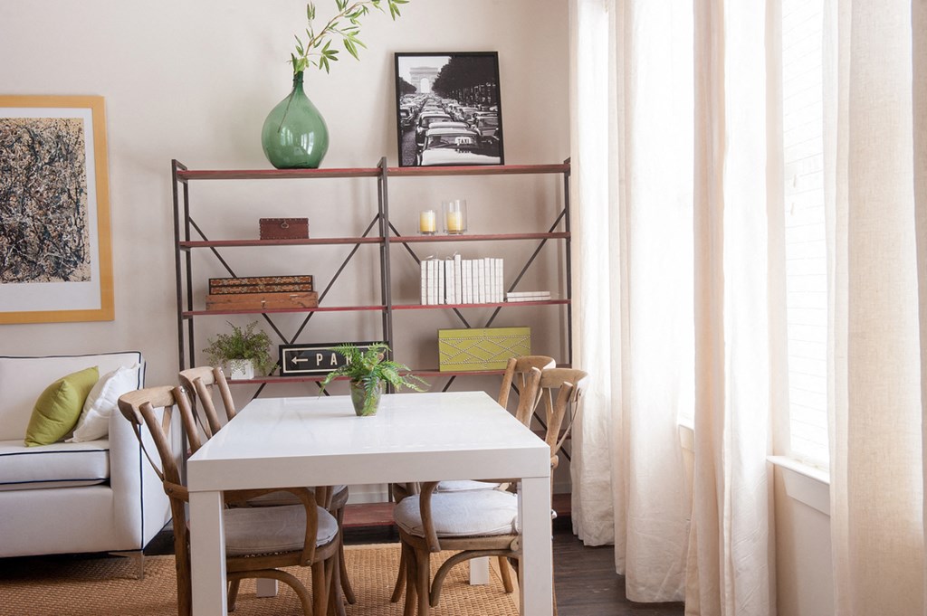 a dining room with a table and chairs and a shelf with a green vase