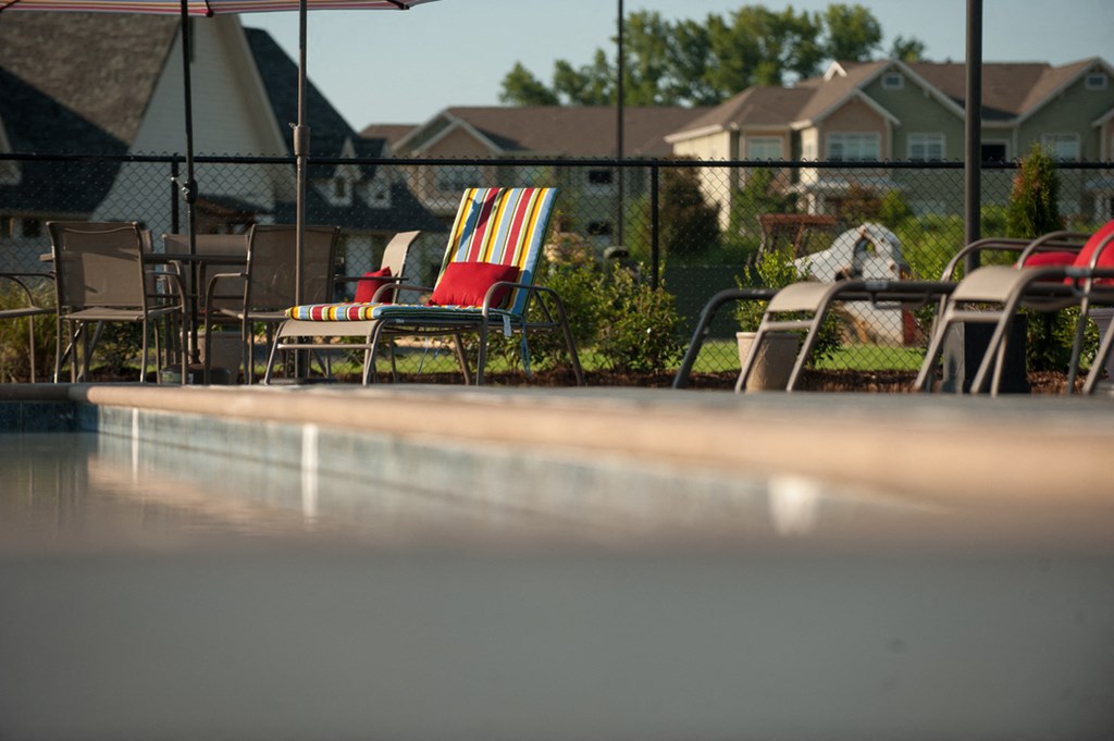 a swimming pool with chairs and umbrellas in a backyard