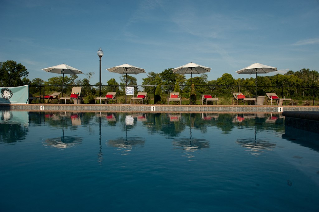 a swimming pool with umbrellas and chairs on the other side of the water