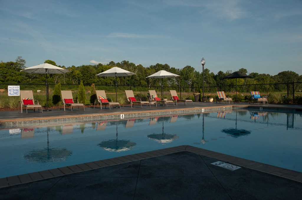 a swimming pool with chairs and umbrellas next to it
