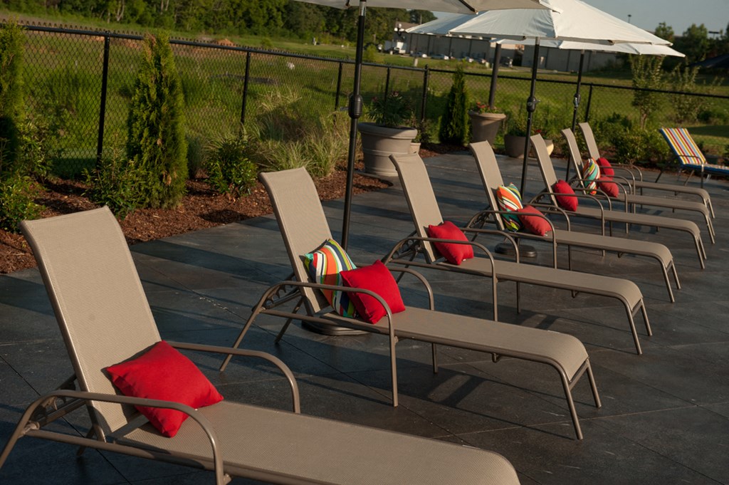 a row of lounge chairs with red pillows on them