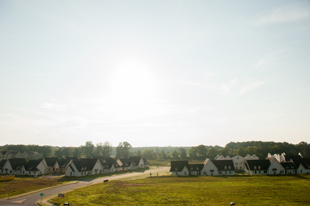 a neighborhood of houses with a green field and a road