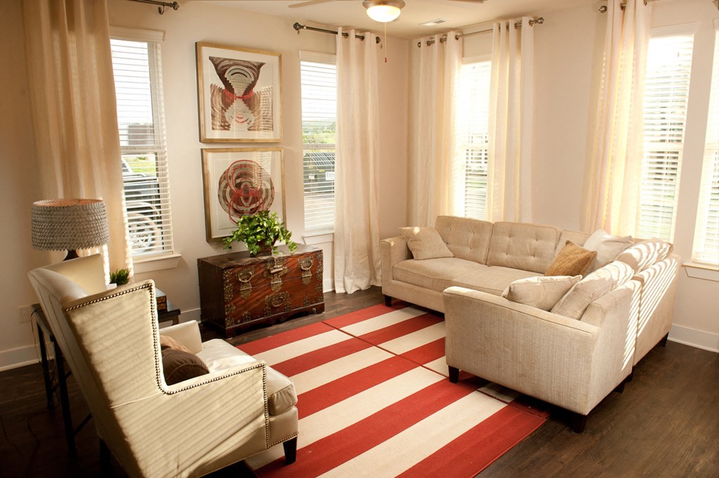 a living room with white furniture and a red and white striped rug