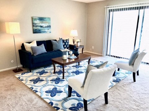 a living room with a blue couch and white chairs