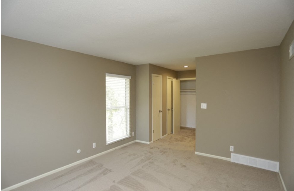 an empty living room and hallway with a door to a closet