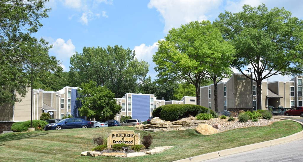 a view of the exterior of an apartment complex with cars parked in front of it