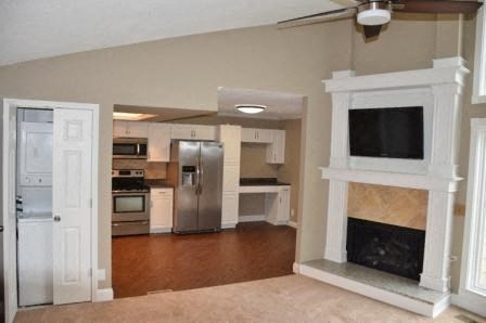 an empty living room with a fireplace and a kitchen