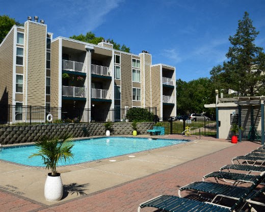 an apartment building with a pool and lounge chairs