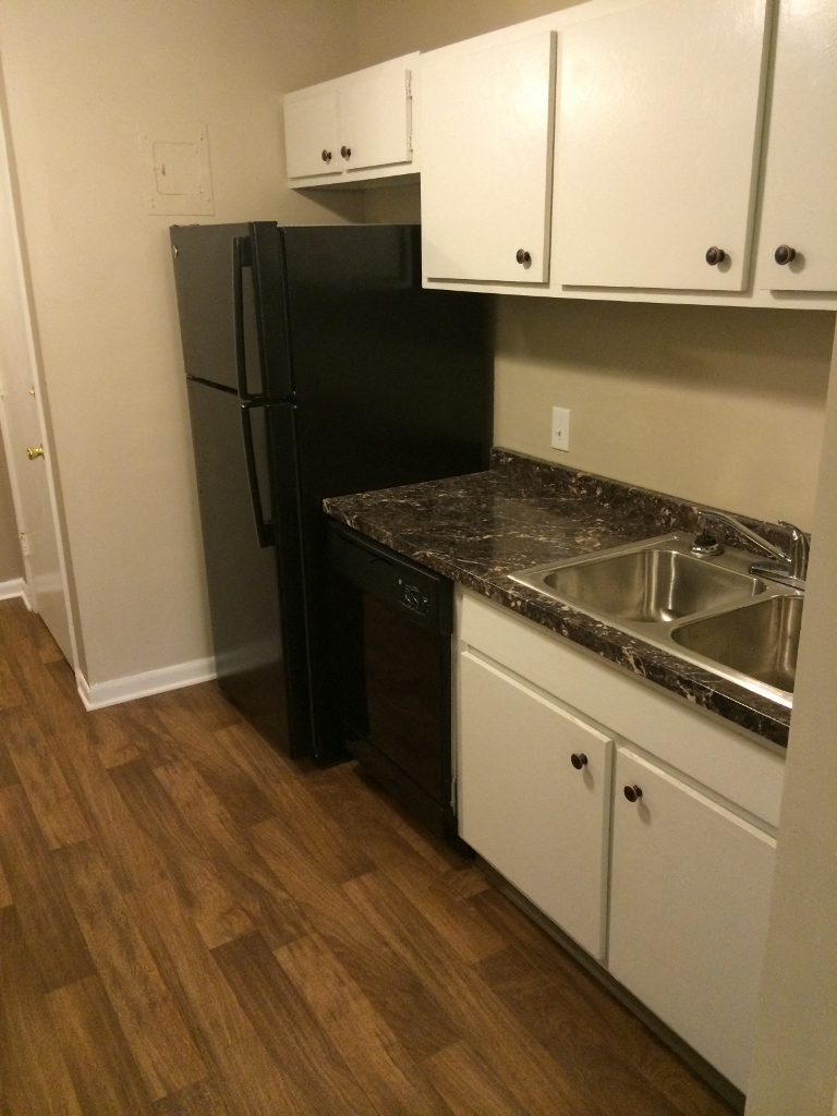 a kitchen with white cabinets and a black refrigerator