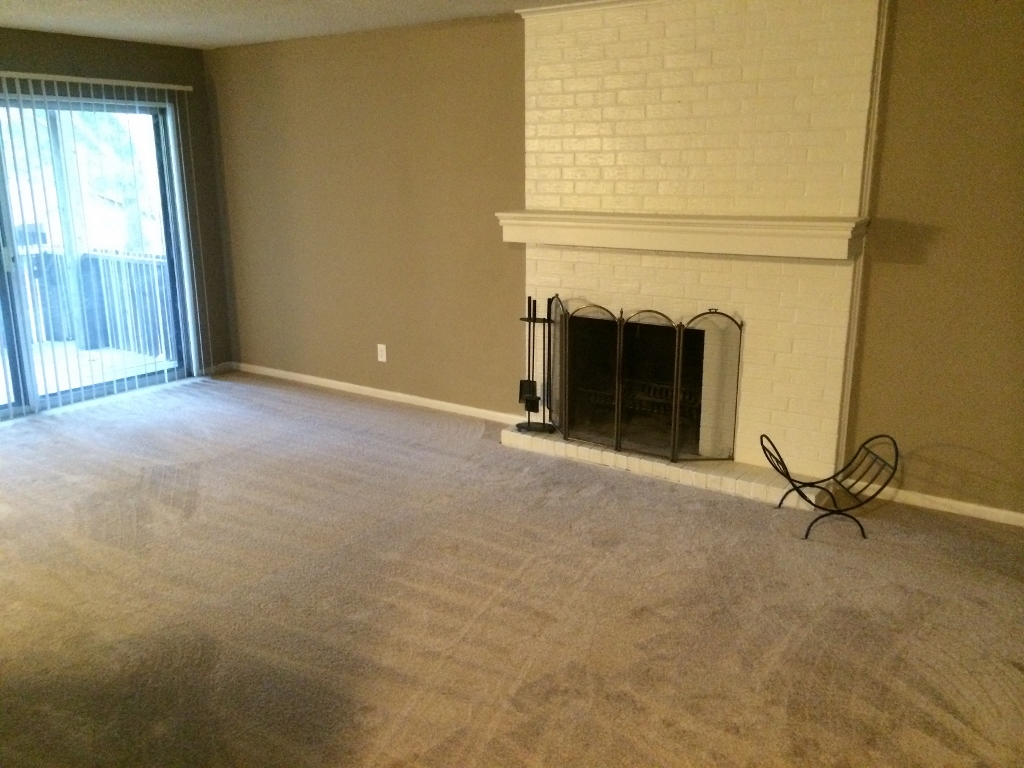 an empty living room with a fireplace and a sliding glass door