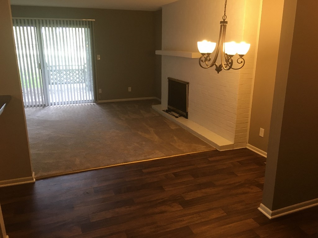 an empty living room with wood flooring and a fireplace
