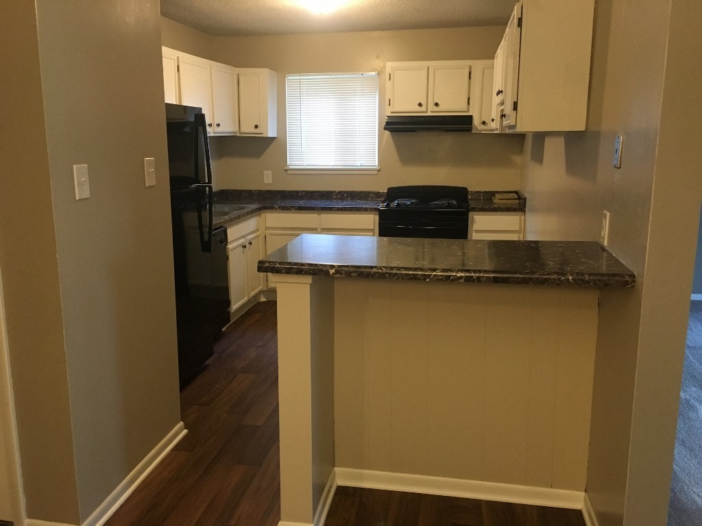 a kitchen with an island and a black refrigerator